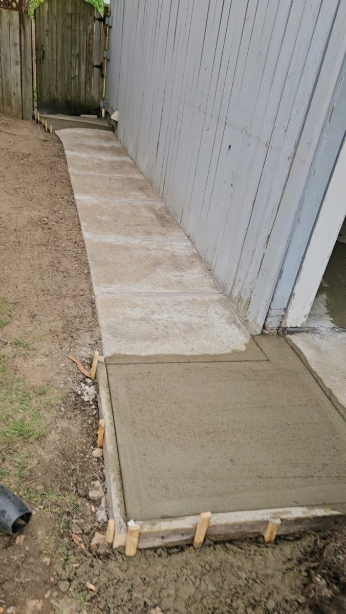 Regraded and repoured concrete walkway directing runoff away from the foundation